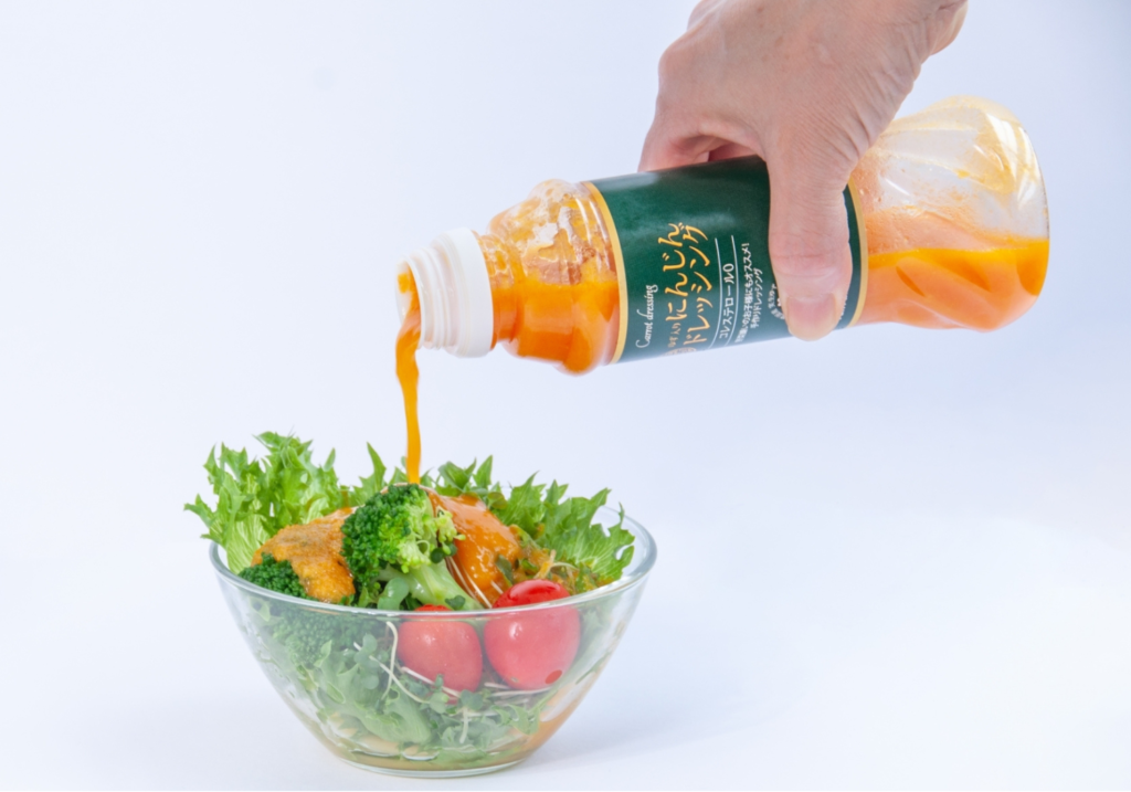 Fun Fun Kitchenのオリジナルブランドドレッシング「にんじんドレッシング」を野菜サラダにかける様子。