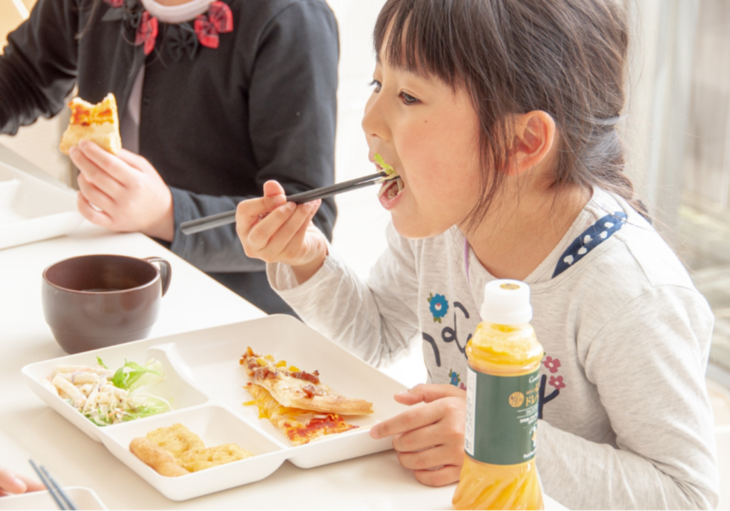 Fun Fun Kitchenのオリジナルブランドドレッシング「にんじんドレッシング」をかけた野菜サラダを食べる女の子の画像。
