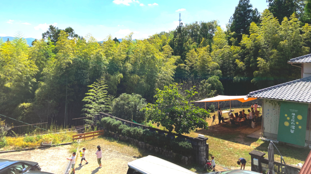 神戸市北区の農村空家を活用したOutdoor Home はこにわ深谷の施設や自然環境が分かる画像。青空の下に子ども連れの家族がバーベキューを楽しんでいます。